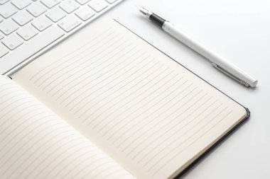 Not defteri, klavye ve dolma kalem ile beyaz tablo. Yukarıdan görüntülemek