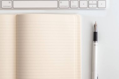 Not defteri, klavye ve dolma kalem ile beyaz tablo. Yukarıdan görüntülemek