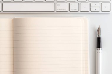 Not defteri, klavye ve dolma kalem ile beyaz tablo. Yukarıdan görüntülemek