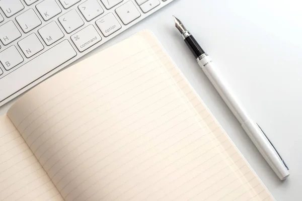 Witte Tafel Met Kladblok Toetsenbord Vulpen Van Bovenaf Bekijken — Stockfoto