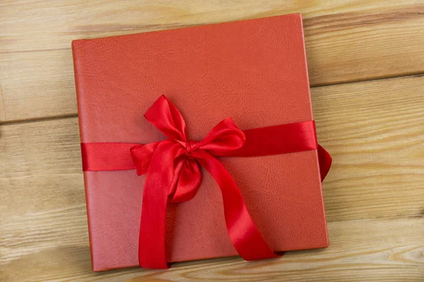 Kırmızı kitap kırmızı kurdele ile. Ahşap arka plan üzerinde kırmızı hediye