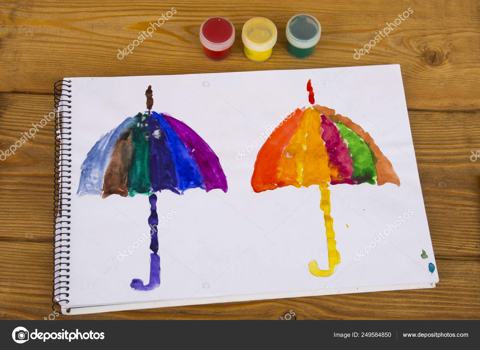 The Child Paints In Watercolor, Painting. Children's Drawing. The Kid Draws An Umbrella In All The Colors Of The Rainbow. Multicolored. Two Umbrellas. Album For Drawing. Kindergarten And School Stock Photo By ©