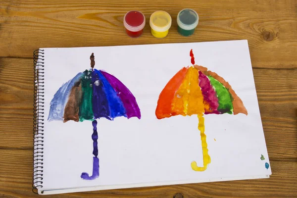 子供は、水彩画で描画されます。子供の図面。子供は、虹のすべての色の傘を描画します。色とりどり。2 つの傘。描画のアルバム。幼稚園・学校 ストック写真