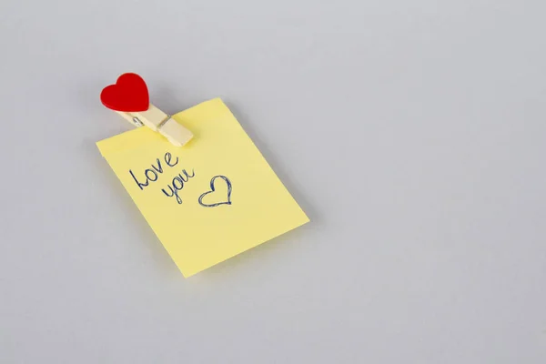 Buzdolabı kapı boş kağıda. Not kağıdı kalp ile. Clothespin bir kalp ile. Yazılı kalem