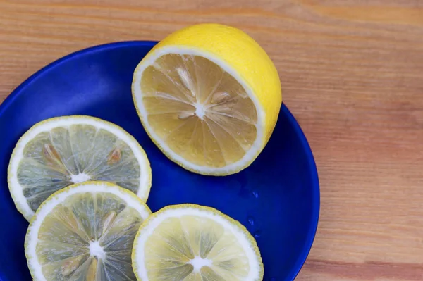 Ahşap bir arka planda limon ile kompozisyon. Mavi plakalı limonlar. Taze sarı limon, yüzük içine dilimlenmiş. Ahşap bir kesme tahtasında limon birkaç dilim