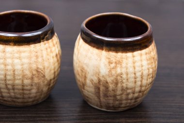 kahverengi arka planda eski sürahi. kahverengi porselen çay bardağı. Seramik kutular. küçük kavanozlar. Kahverengi kil yemekleri. kil malzeme yapılmış kil kaplar. Vintage ahşap masada iki bardak sıcak kahve