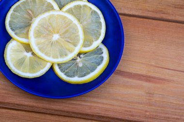 Ahşap bir arka planda limon ile kompozisyon. Mavi plakalı limonlar. Taze sarı limon, yüzük içine dilimlenmiş. Ahşap bir kesme tahtasında limon birkaç dilim