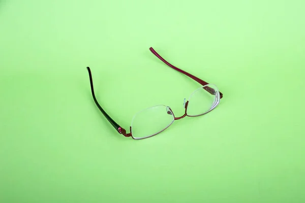 Glasses of a woman on a green background. Red frame glasses on green background. Myopia and hyperopia. Red rim glasses
