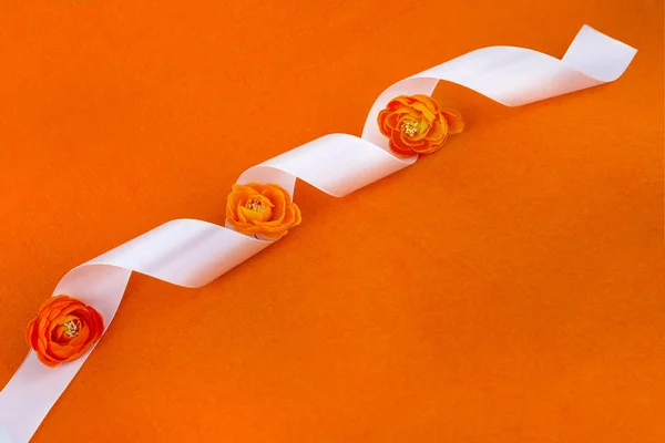 Hediye turuncu kurdele. Kurdele ve çiçek. Turuncu arka planda beyaz kurdele. Dikiş atölyesi. Küçük dekoratif turuncu çiçek