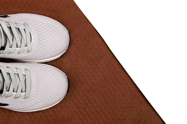 Kahverengi arka planda beyaz spor ayakkabılar. Beyaz arka planda erkek ayakkabıları. Gri spor ayakkabılar