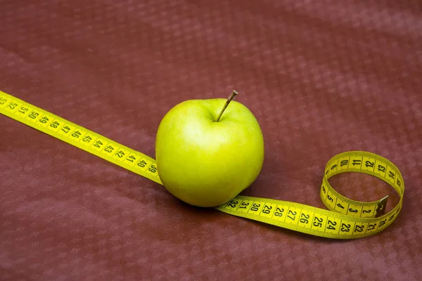 Green apple and ribbon on brown background. Measuring tape and apple. Fruits for weight loss. low calorie product. apple juice.