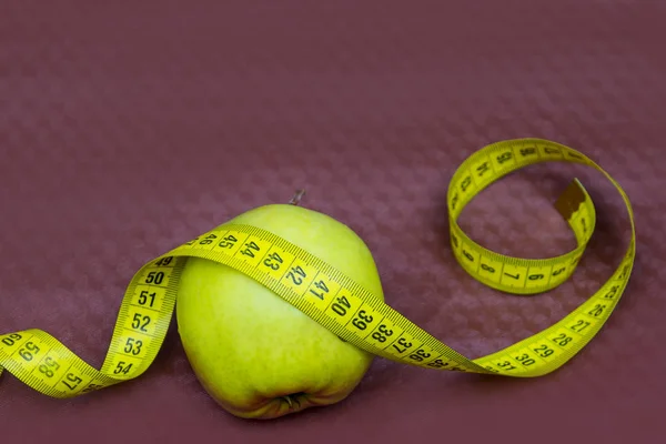 Green apple and ribbon on brown background. Measuring tape and apple. Fruits for weight loss. low calorie product. apple juice.