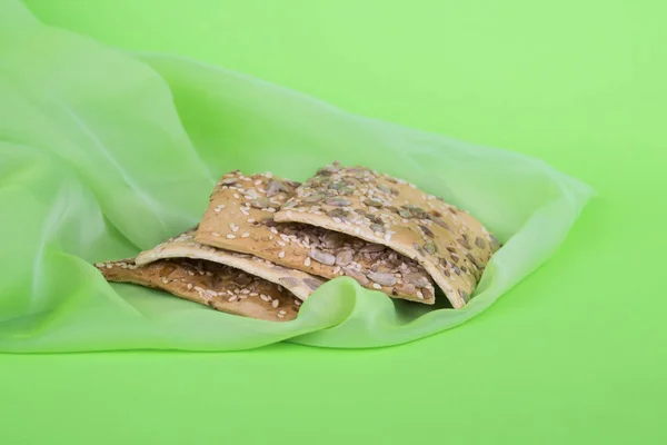 Biscuits sur tissu vert. Biscuits diététiques aux graines. Pâtisserie feuilletée sur fond vert — Photo