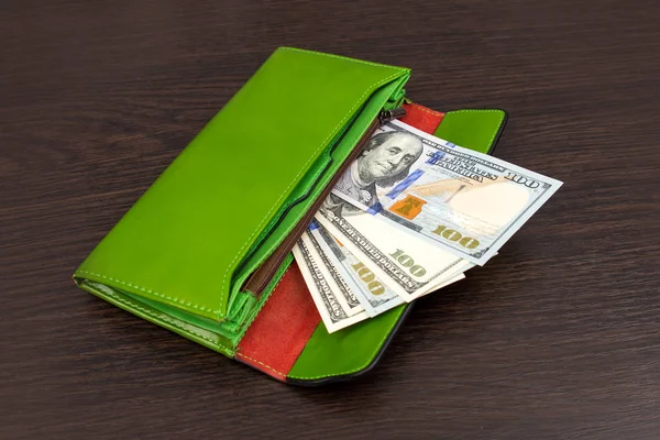Big green wallet with money on a brown background. The wallet in which the dollars lie. Concept of saving money. a stack of money in a wallet. Full wallet.