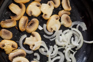 Kavrulmuş sosisli, soğanlı, tavada kızartılmış şampiyon. Tavada soğan olan mantarlar. Öğle yemeği ve akşam yemeği. Kızarmış soğan halkaları..
