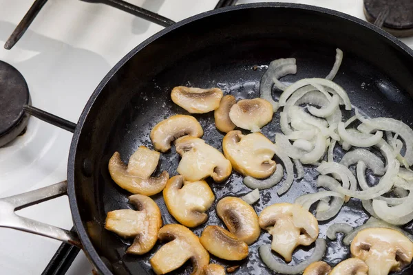 フライパンに玉ねぎをスライスしたシャンピニオンを揚げ 鍋に玉ねぎとキノコ 昼食と夕食を調理する 揚げ玉ねぎリング ロイヤリティフリーのストック写真