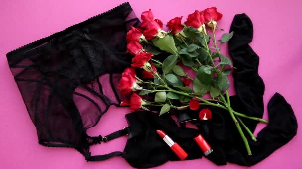 Sexy pásek s punčochami a červenými růžemi, červená rtěnka na růžovém pozadí horní pohled. Okvětní lístky červené růže jemně nalít na punčochy s opaskem