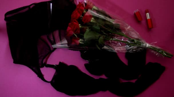 性感的女性腰带 袜子和花束红玫瑰 红色口红躺在微光闪烁的粉色背景顶部的观点 展示主义的概念 — 图库视频影像