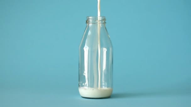 Fresh Farm Milk Pouring Glass Bottle Half Blue Background Front — Stock Video