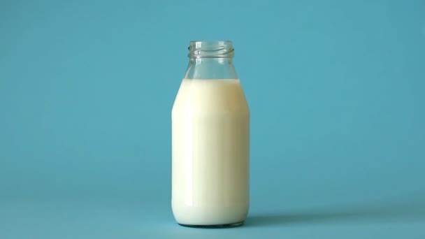 Kadın Eli Mavi Arka Planda Süt Dolu Şişeye Pembe Renkli — Stok video
