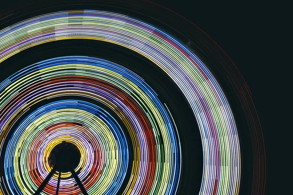 Colorful light streaks made by a ferris wheel at night
