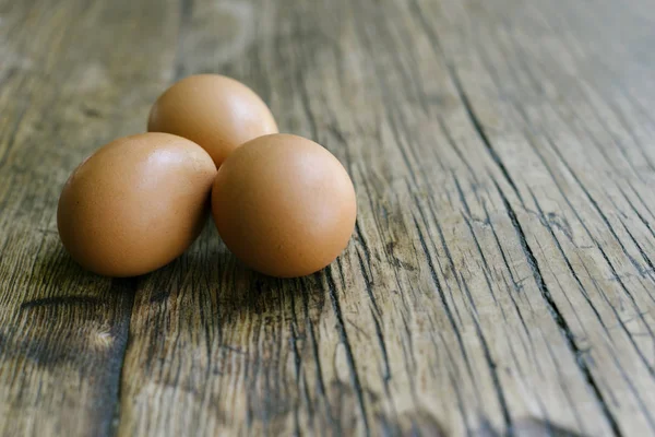 View of 3 fresh eggs on a farm table with copy space
