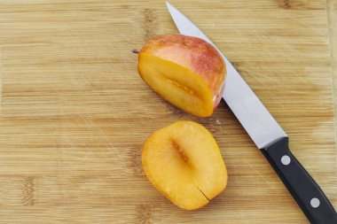 Yarım bir ahşap kesme tahtası üzerinde bir amigo pluot doğranmış