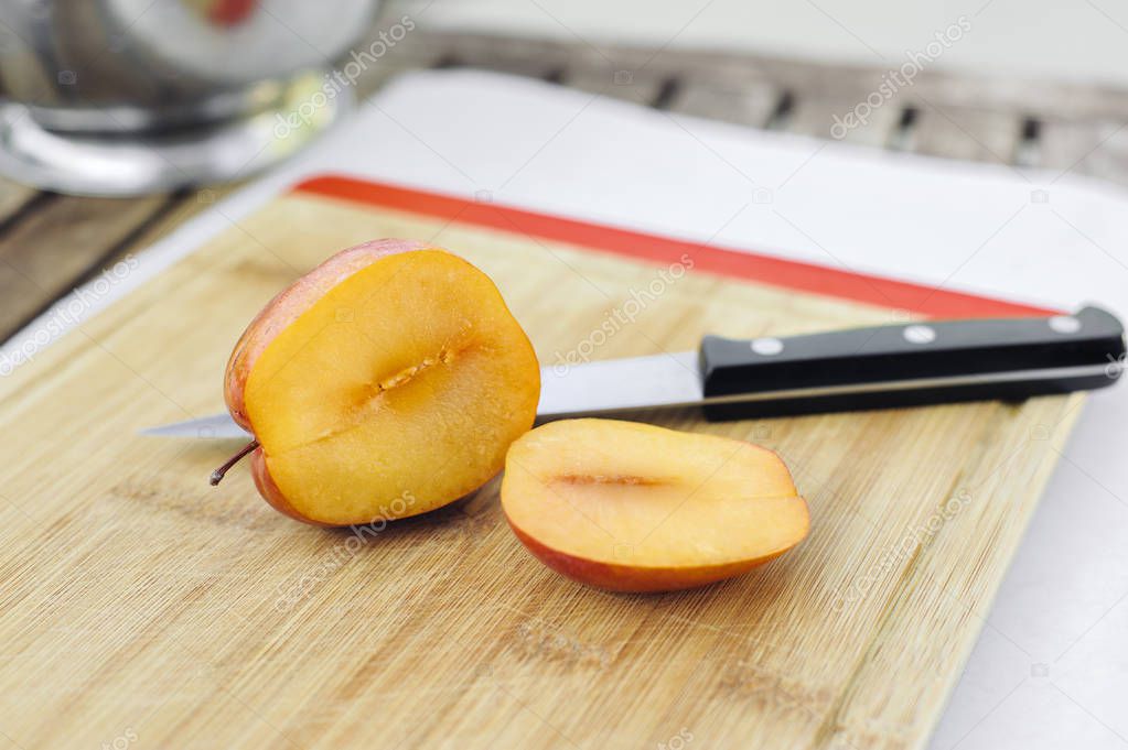 Sliced open amigo pluot fruit on a wood chopping board