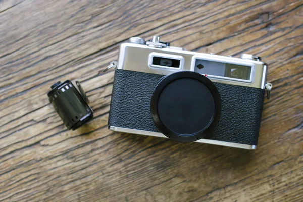 Old retro film camera on a wood table with a film roll