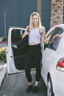 Genç beyaz kız arabası ile spor çantasını çıkar ve egzersiz giyim giyinmiş. Happy bin yıllık