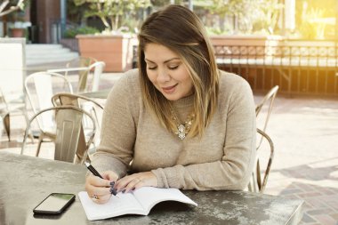 Onun hedefleri açık havada bir kafede bir günlükteki aşağı genç latina yazıyor