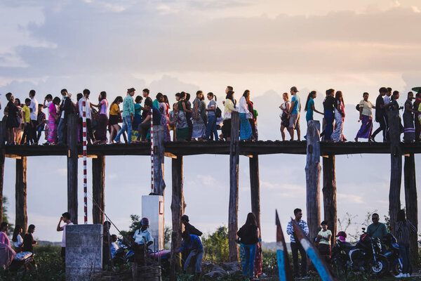 Люди, идущие по мосту U-Bein на сцене заката в Амарапуре, Мандалай, Мьянма
