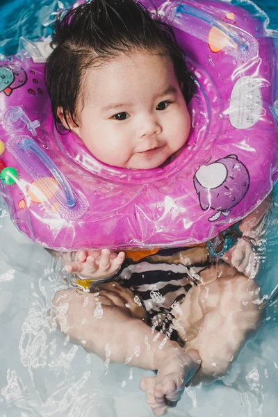 Close up portrait Asian cute baby girl 4 month-old in kit inflatable pool