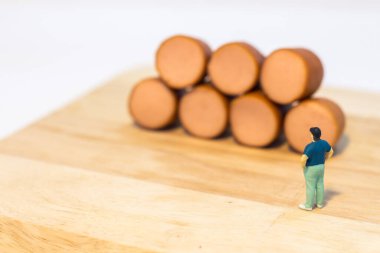 Minyatür insanlar: Şişman adamı kapatın ve beyaz arka planda izole edilmiş sosislere bakın (Gıda kavramı)