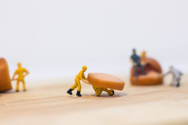 Minyatür insanlar: Kapatılan işçiler beyaz arka planda izole edilmiş sosisler üzerinde çalışıyorlar (gıda kavramı)