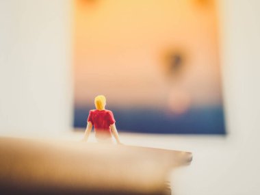 Minyatür insanlar, pasaport üzerinde oturan genç adam tapınağın üzerinde yüzen sıcak hava balonunun fotoğrafına bakıyor. (Turizm konsepti)