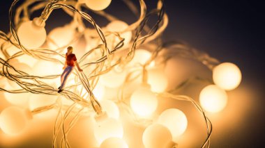 Minyatür insanlar, elektrikli tellerin üzerinde oturan genç adamı kapatın.