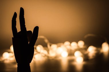 Tahta el silueti, arka planda altın bulanık ışıklar.