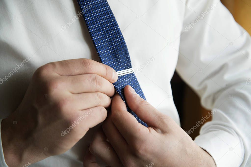 man putting on cuff-links as he gets dressed in formal wear .Groom's suit. Man in a suit fixing his tie. Monday morning working day.