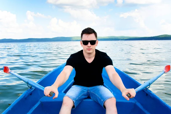 Young white male rowing on lake, man in a boat rowing on the lake