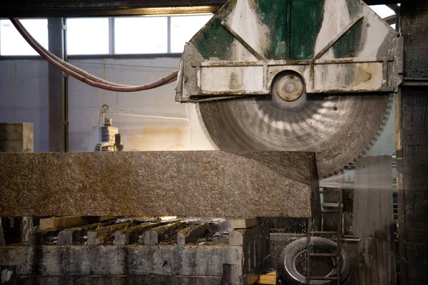 Granite processing in manufacturing. Cutting granite slab with a circular saw.