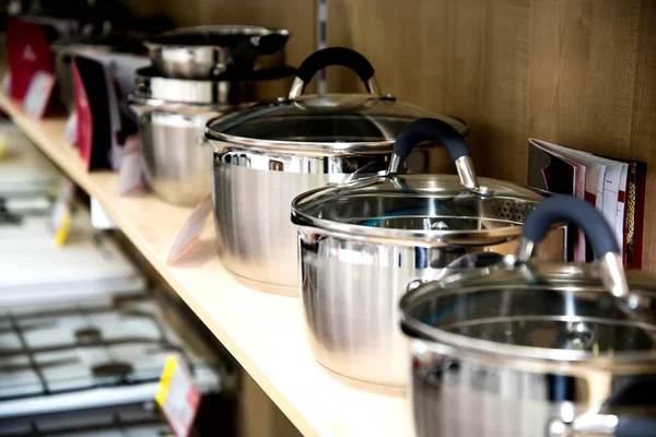 Комплект посуды из нержавеющей стали на полках магазина, крупным планом — стоковое фото