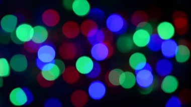 Noel ışıklarının soyut arka planı. Düzgün hareket. Rüzgardan titriyor. Defodaklanmış görüntü. Renkli Noel ışıkları.