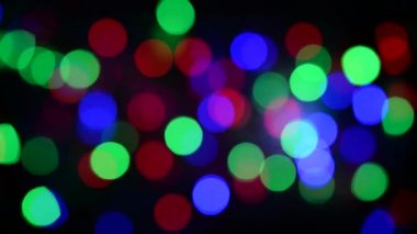 Noel ışıklarının soyut arka planı. Düzgün hareket. Rüzgardan titriyor. Defodaklanmış görüntü. Renkli Noel ışıkları.