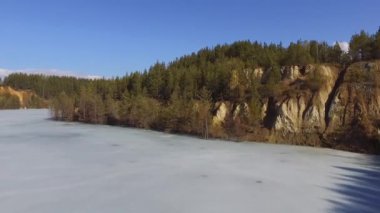 Donmuş bir gölün kıyısındaki çam ormanının kenarı. Kış, temiz hava, Drone'dan. açılış çekimi