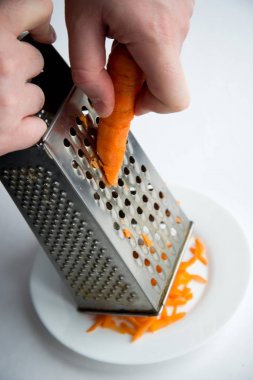 taze havuç rendeleyin, aşçı bir rende havuç ovuşturuyor.