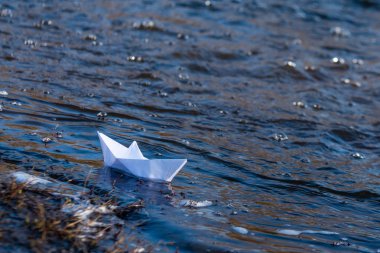 Çalkantılı bir su dere üzerinde bir kağıt tekne akışı ile mücadele. Küçük kağıt tekne nehir boyunca akıyor.
