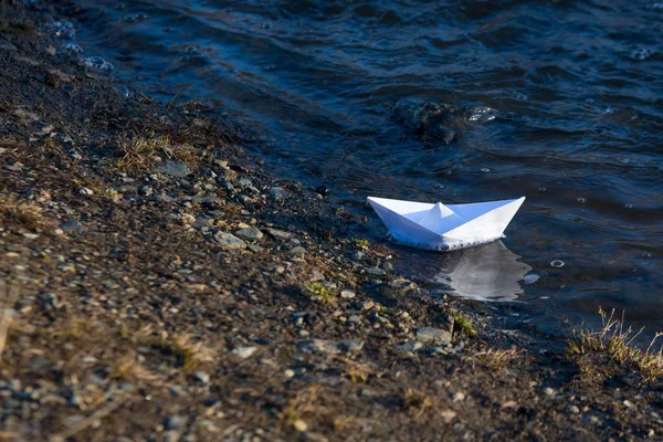 Barco de juguete de papel blanco en agua azul cerca de la orilla — Foto de Stock