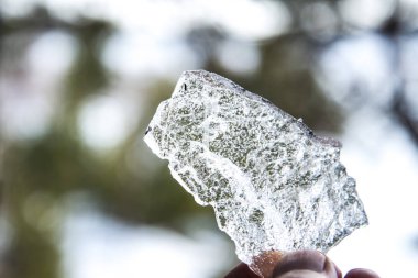 Elinde büyük bir parça parlak buz, buz elinde eriyor.
