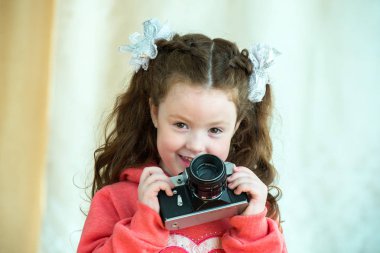 Açık arka planda vintage kamera ile küçük kız. Gülümseyen sevimli çocuk kız 4-5 yaşında